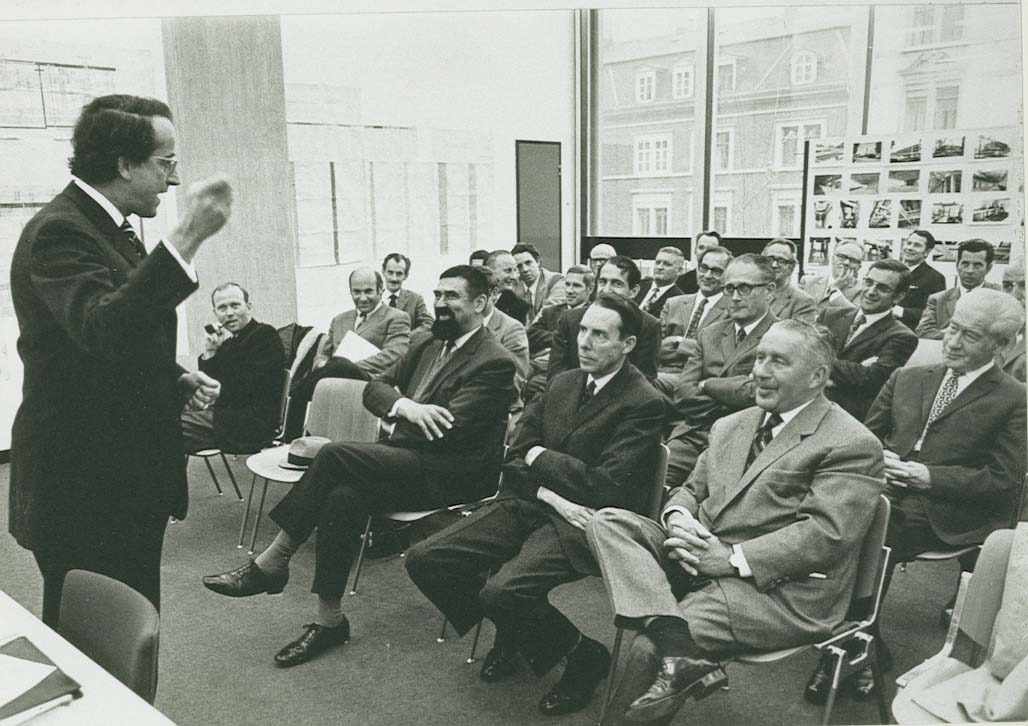 Der Architekt des Biozentrums Martin Burckhardt erklärt bei einer Begehung des Biozentrums am 26. 10. 1971 das Konzept des Neubaus. In der ersten Reihe sitzen von links nach rechts Regierungsrat Arnold Schneider, Bundesrat Hans Peter Tschudi und Regierungspräsident Max Wullschleger.